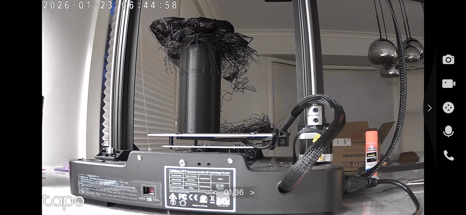 Tangled black filament piled around a failed print on the Creality Ender-3 printer.